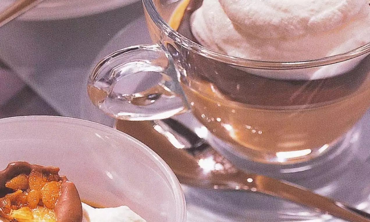 Transparent glass cups with layered desserts, whipped cream topping, and caramel accents beside a plastic cup with nut garnish