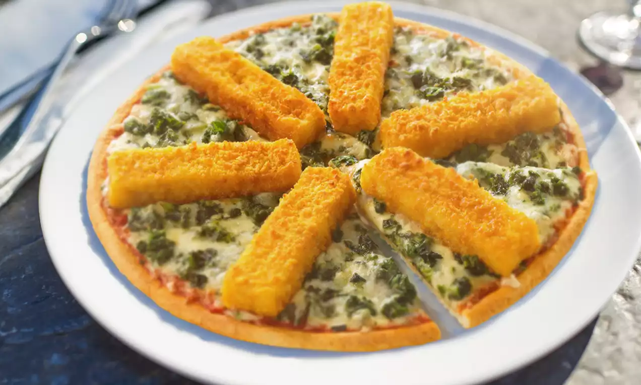 Runde Pizza mit knusprigem Rand, belegt mit goldbraunen Fischstäbchen, grünem Gemüse und geschmolzenem Käse auf weißem Teller