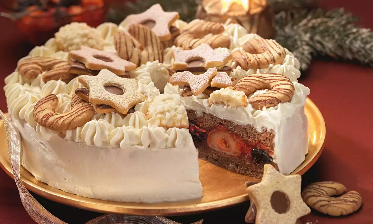 Okrugla bijela torta s bogatim slojem šlaga, voćnim punjenjem i dekoracijom od zvjezdastih keksa na zlatnom tanjiru