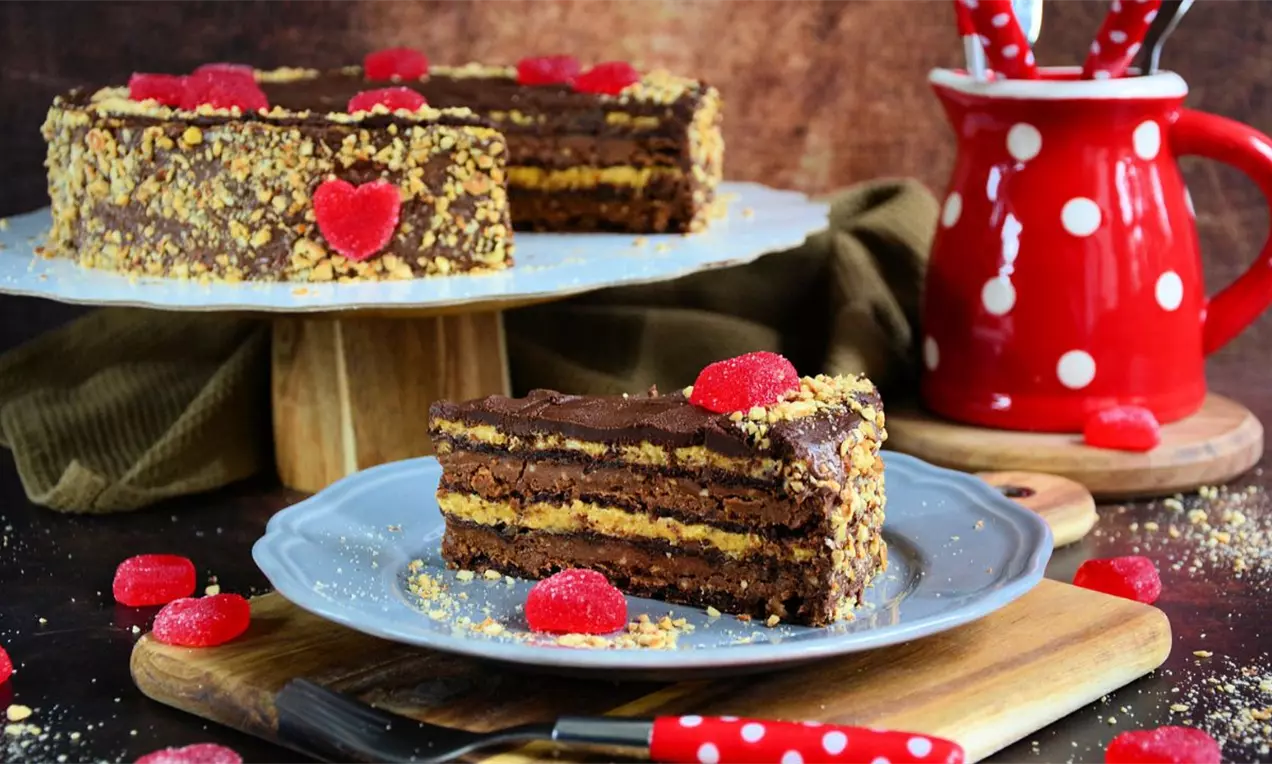 Četvoroslojna čokoladna torta sa naizmeničnim tamnim i svetlim filom, prelivena glatkom čokoladom i posuta seckanim lešnicima.