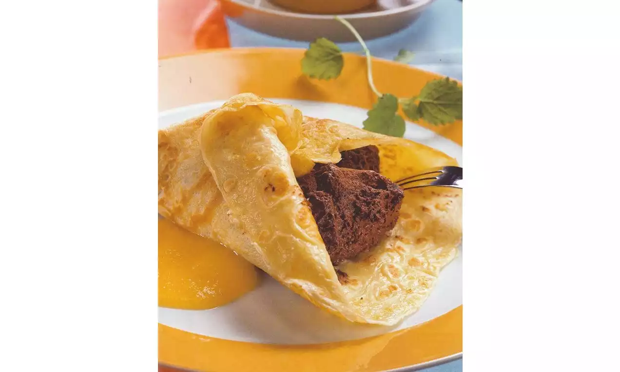 Goudgele crêpes gevuld met luchtige bruine chocolademousse, opgediend op een wit bord met een oranje rand, gegarneerd met een vleugje saus
