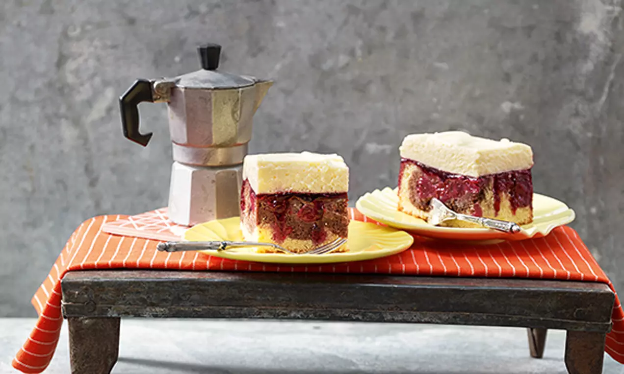 Квадратни парчета черешова торта с кремообразен ванилов пудинг, сочен червен плод и нежно златист блат, сервирани върху жълти чинии