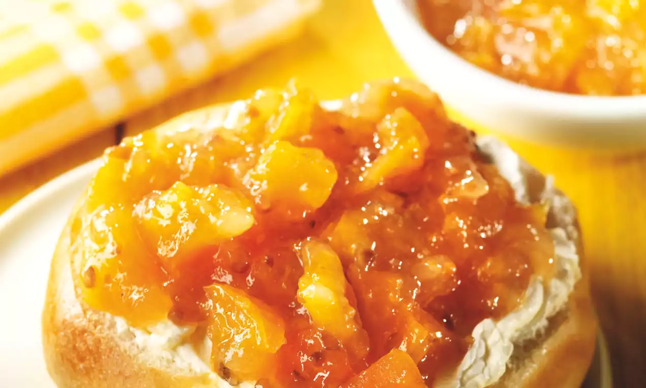 Brioche dorée moelleuse garnie de fromage frais et confiture brillante d'abricots et bananes sur une assiette blanche