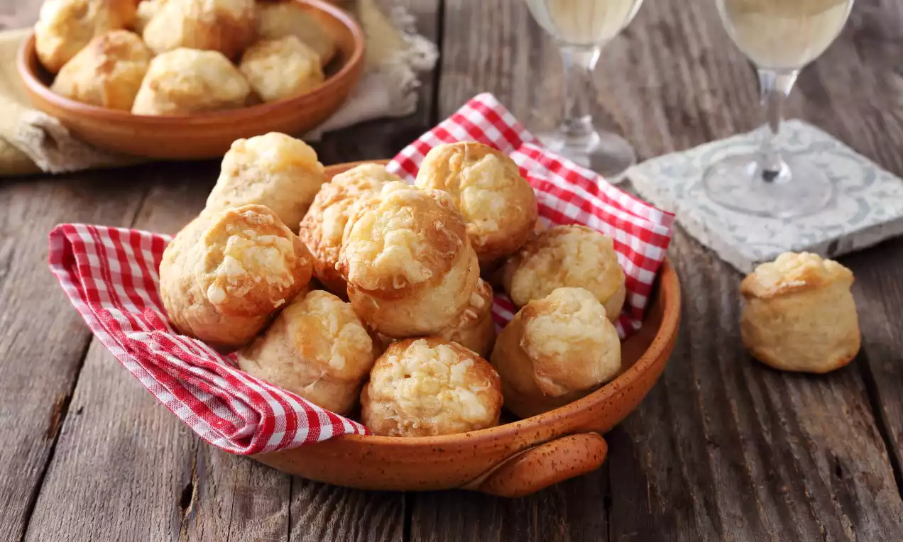 Aranybarna, omlós krumplis pogácsák ropogós sajtkéreggel piros-fehér kockás kendőn, rusztikus kerámia tálban faasztalon.