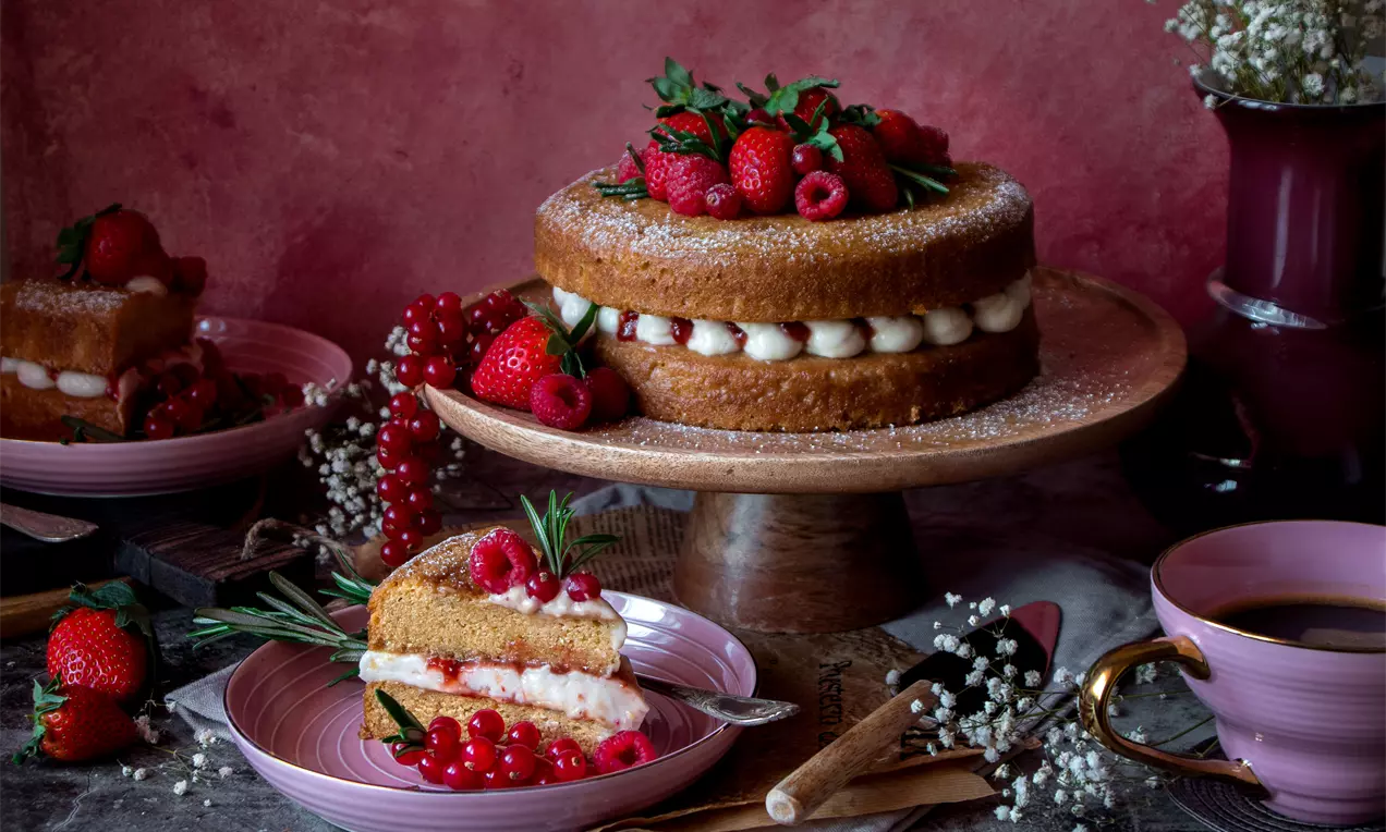 Веган торта Виктория с два златисти блата, крем побел между тях, украсена с пресни ягоди, малини и поръсена с пудра захар върху дървена поставка
