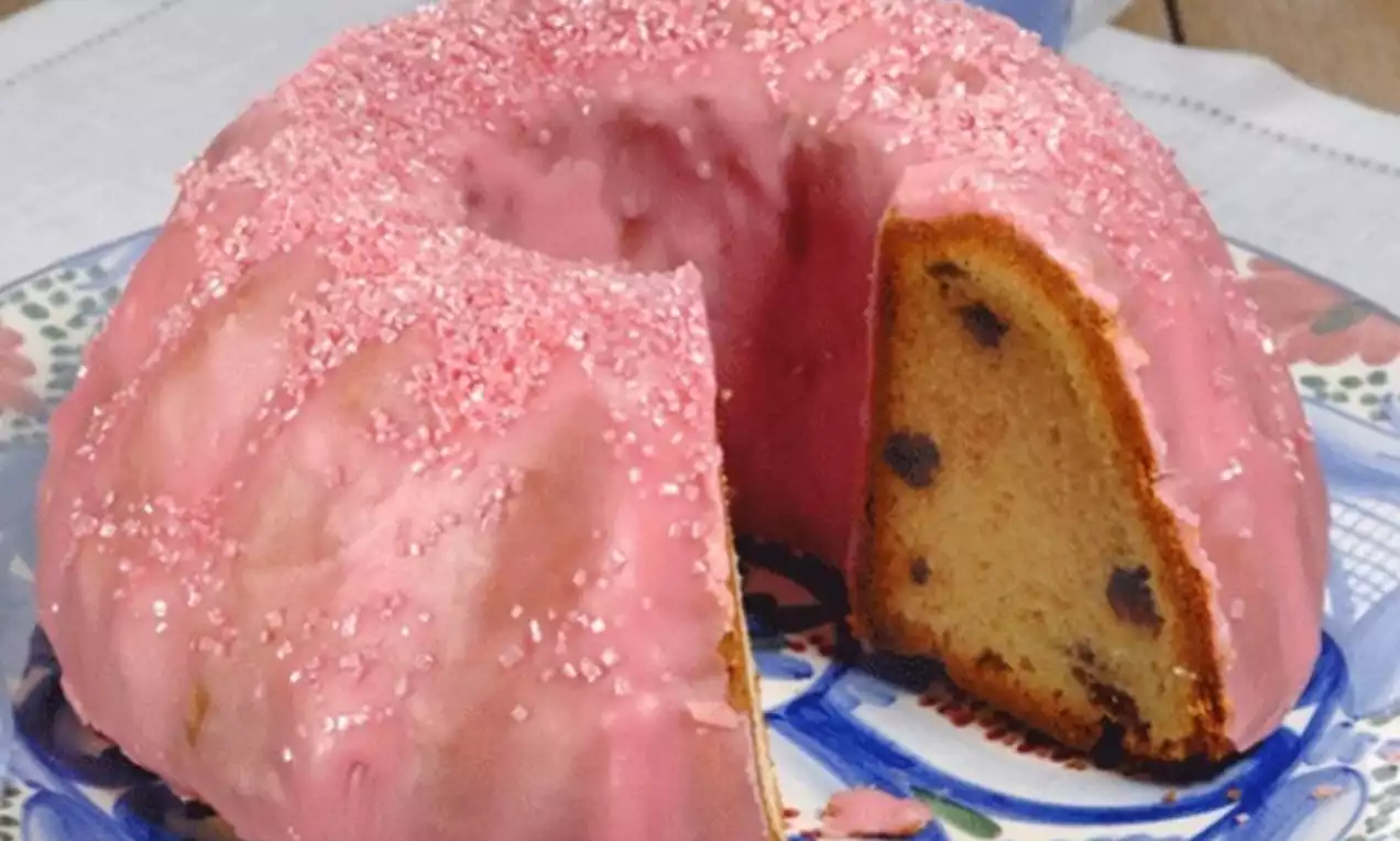 Vruchtentulband met roze glazuur en suikerkorrels op een decoratieve schaal, met een gesneden stukje dat de vulling met stukjes toont