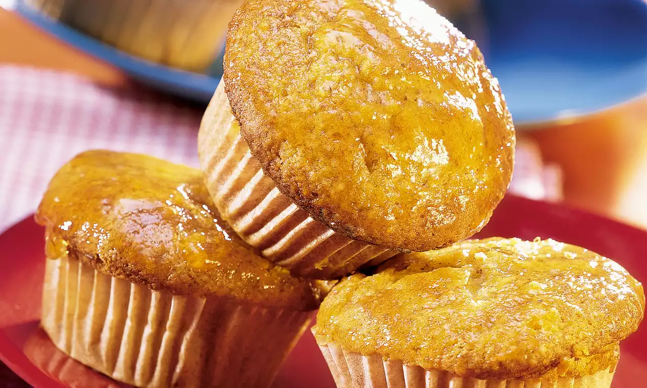 Muffins dorés et brillants à la surface bombée, disposés en pile sur une assiette rouge avec une texture moelleuse et tendre