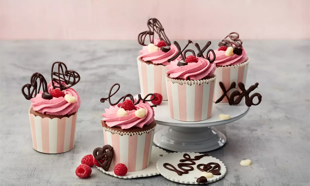 Schoko-Himbeer-Cupcakes mit dunklem Schokoteig, weißem Mascarpone-Frosting, frischen Himbeeren und Schokospänen auf Teller