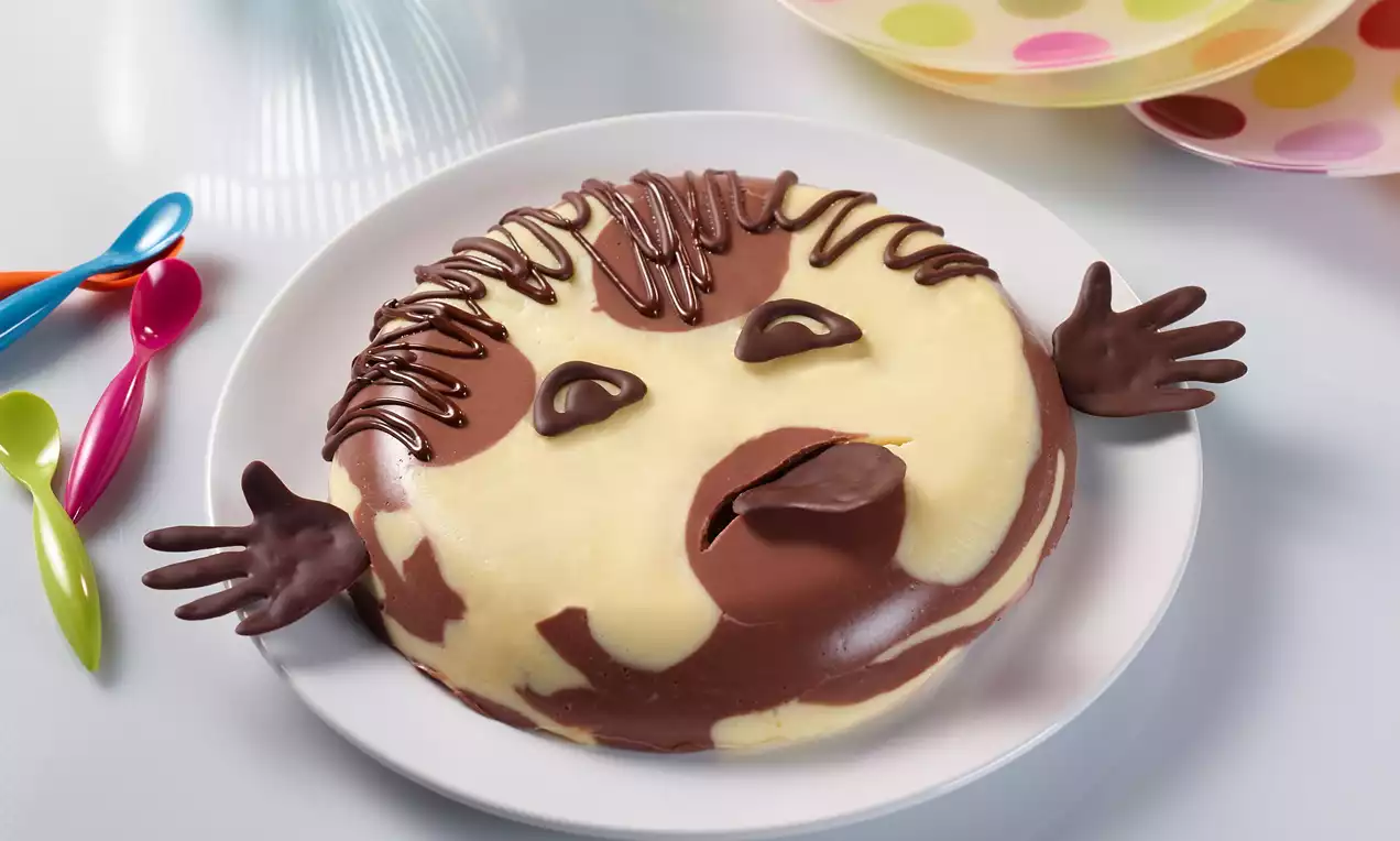 Een pudding met contrasterende lagen van romig geel en rijke chocolade, gegarneerd met chocolade details op een wit bord met kleurrijke lepels