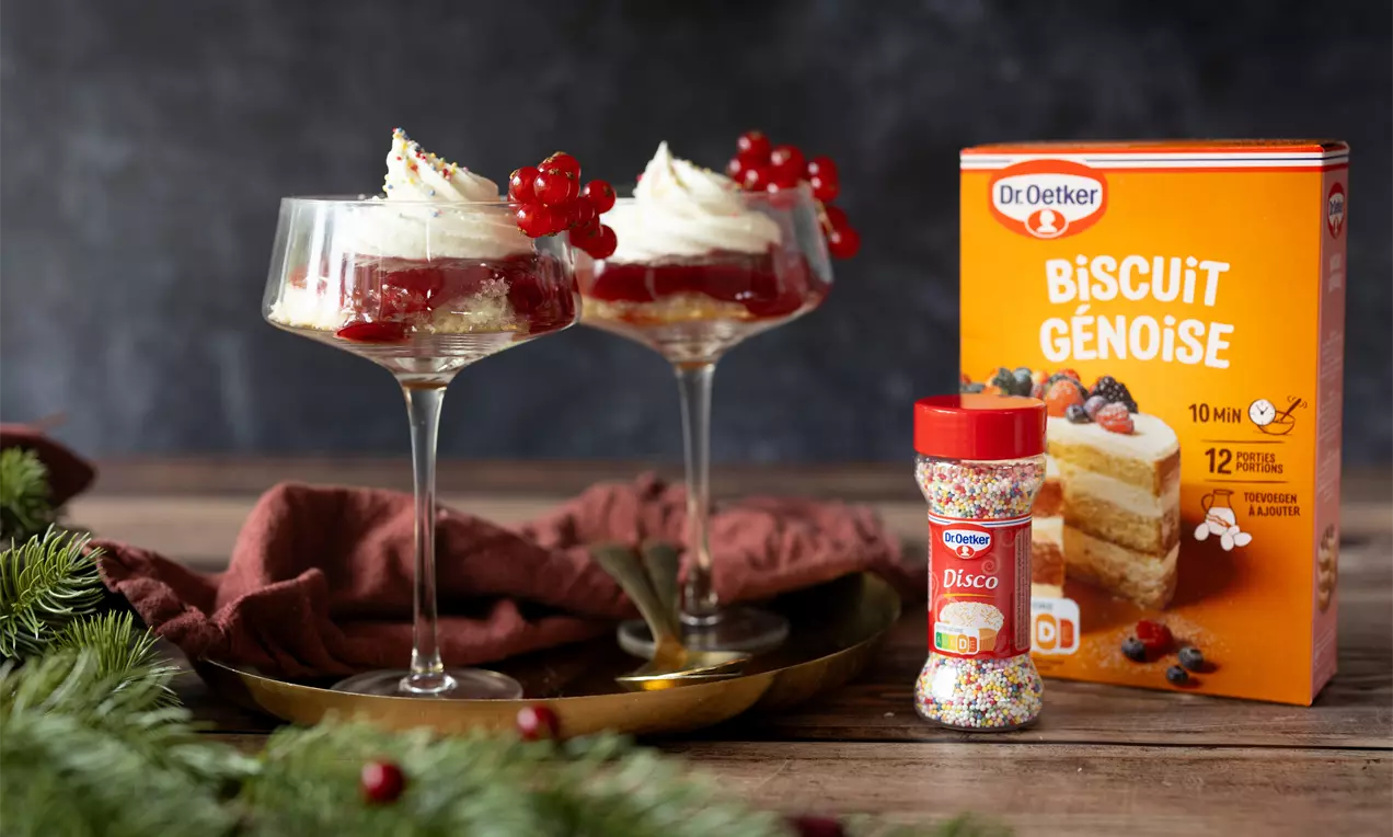 Mini kersttrifle met luchtige biscuit, frambozenconfituur en slagroom in stijlvolle glaasjes.