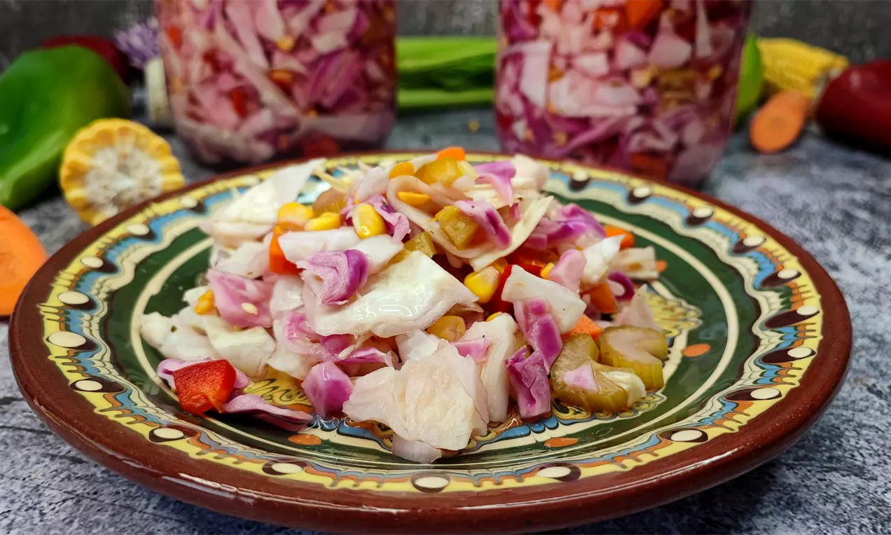 Шарена туршия с ярки парчета зеле, морков, царевица и червен пипер в сладко-кисела саламура върху традиционна цветна чиния