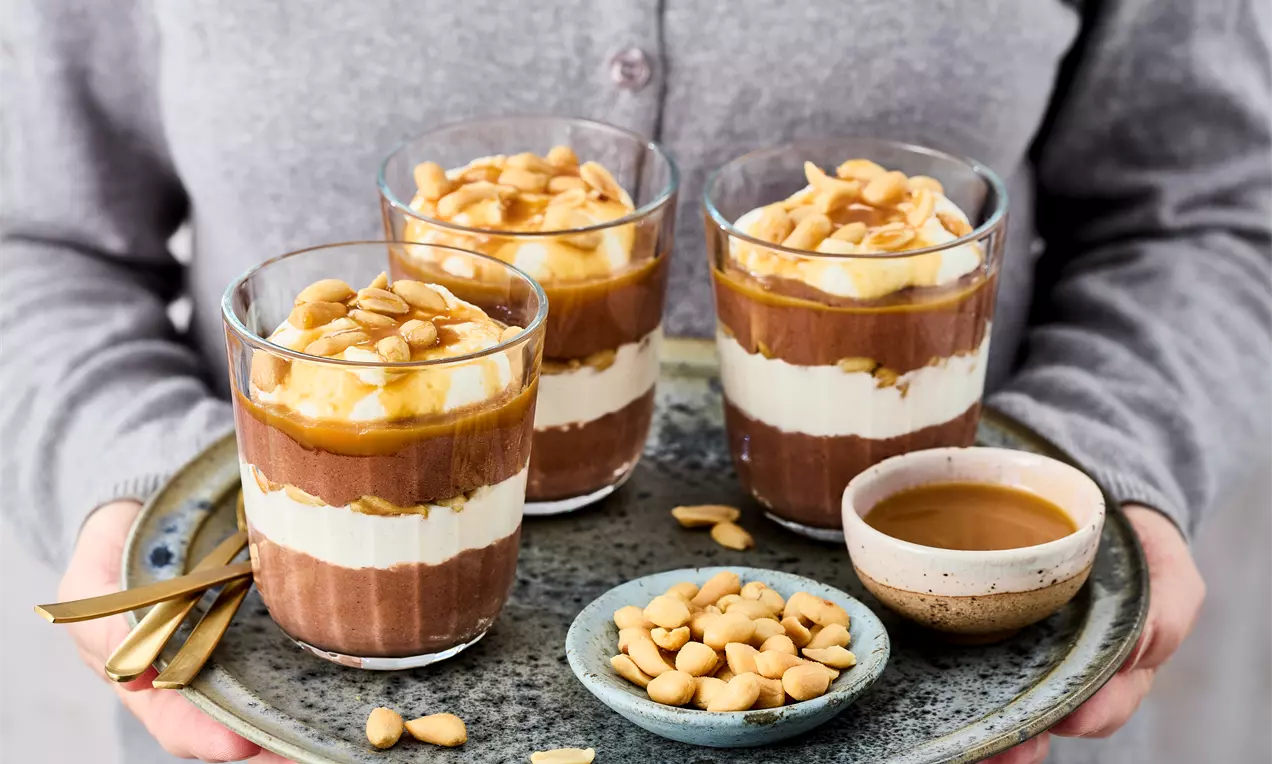 Schoko-Erdnuss-Dessert mit cremiger Erdnussbutter, Schoko-Mousse und knackigen Erdnüssen – schnelles Rezept für süßen Genuss mit Karamell-Topping.