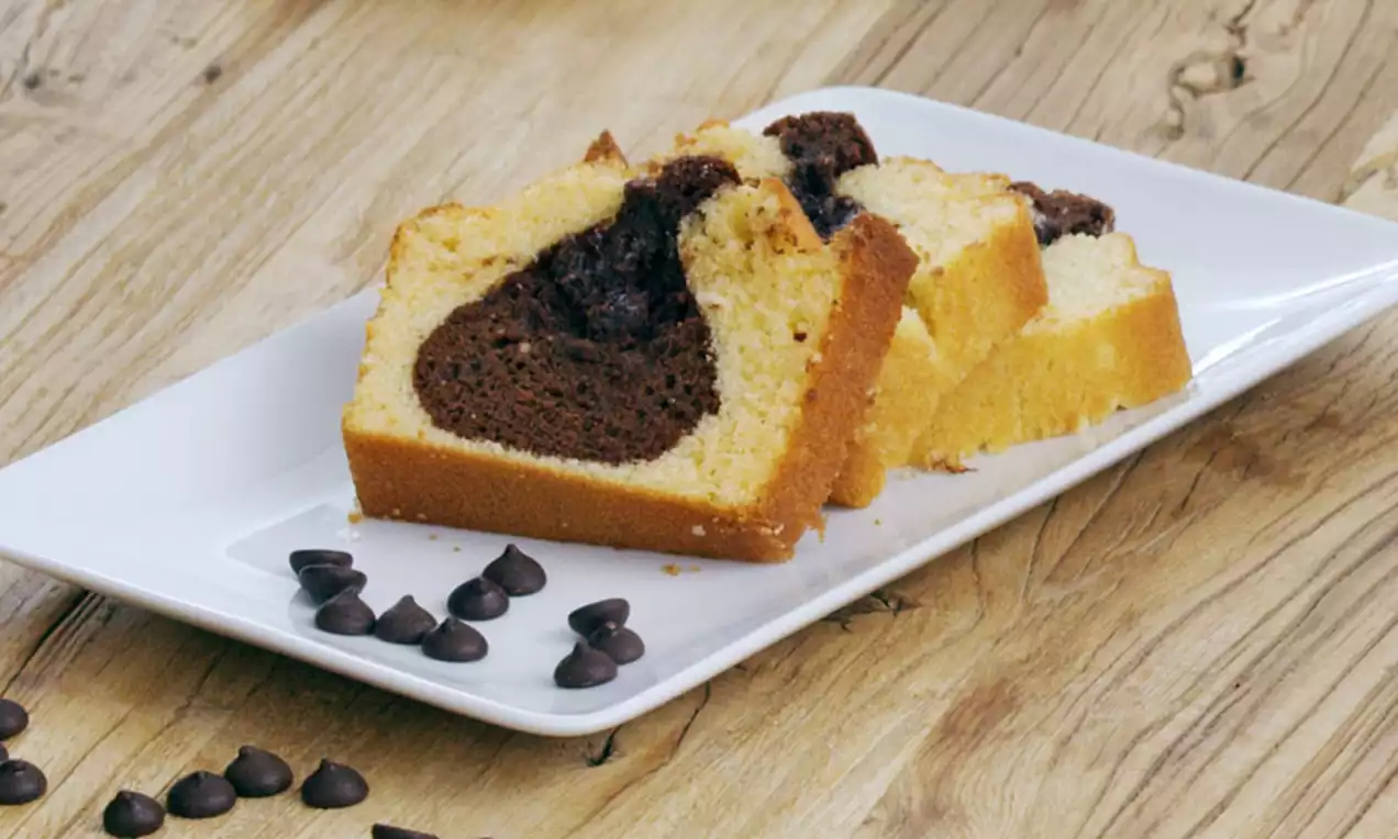 Plakken marmercake met golvende lagen van goudgele vanillecake en diepbruine chocoladecake, geserveerd op een wit rechthoekig bord