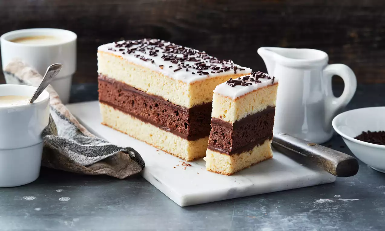 Gâteau rectangulaire en trois couches alternées de génoise jaune pâle et mousse chocolatée, glacé au sucre avec vermicelles au chocolat