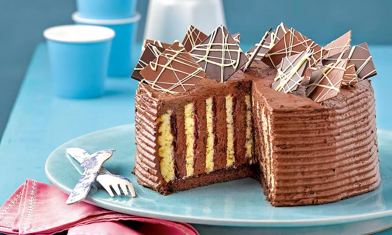 Gâteau roulé au chocolat avec une texture striée enveloppée, rayures alternées jaunes et brunes à l'intérieur, décoré de fins éclats chocolatés