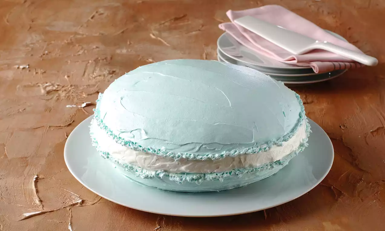 Açık mavi kabuğu ve beyaz krema dolgulu, yuvarlak makaronu andıran pasta, beyaz tabakta pembe bir peçeteyle sunulmuş