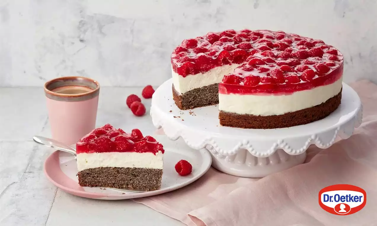 Makový dort na bílé keramické podložce, vrstvený tmavou makovou základnou, světlým krémem a lesklým malinovým želé, zdobený čerstvými malinami