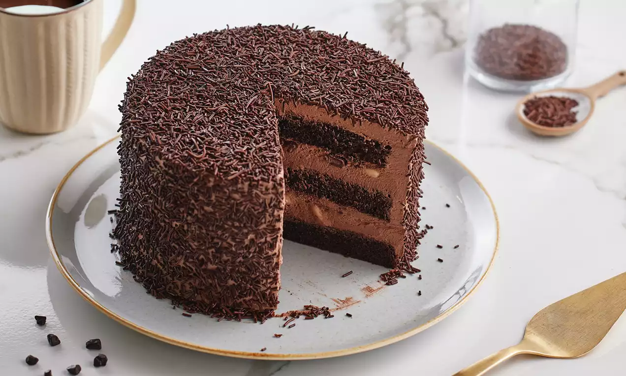 Kat kat koyu kahverengi pandispanyadan oluşan, muzlu kreması ve çikolata parçacıklarıyla kaplanmış yuvarlak bir çikolatalı pasta