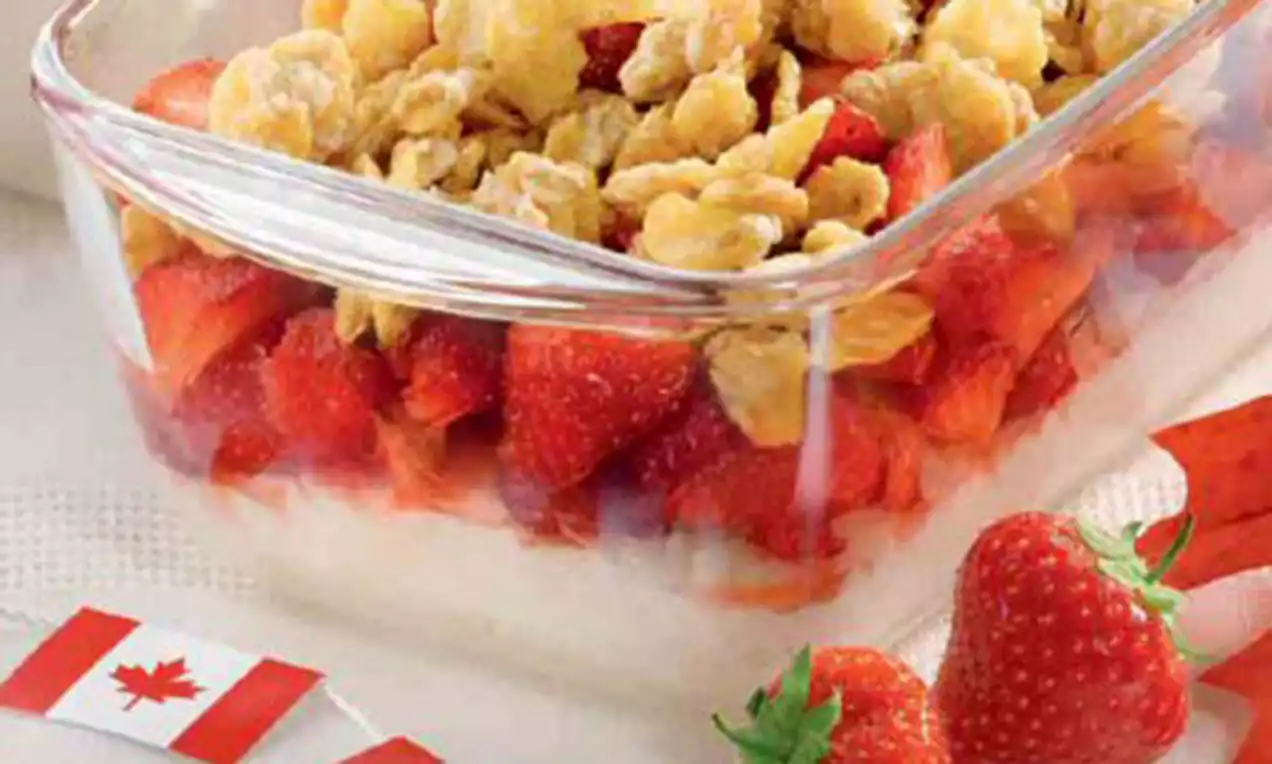 Erdbeer-Milchreis-Crumble in einer rechteckigen Glasform, mit frischen roten Erdbeerstücken, goldbraunen Streuseln und einer kanadischen Flagge drapiert
