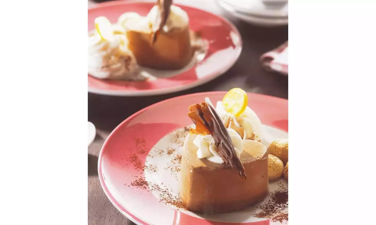 Coeurs glacés couleur caramel ornés de crème fouettée, chocolat en spirale et tranches de kumquat sur une assiette rouge