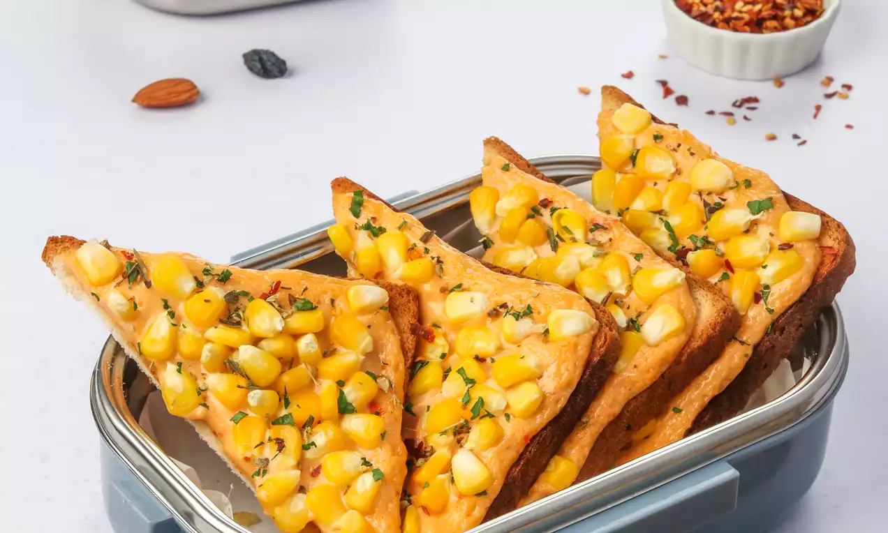 Golden toasted triangles topped with melted yellow cheese and vibrant corn kernels, sprinkled with herbs, arranged in a blue container