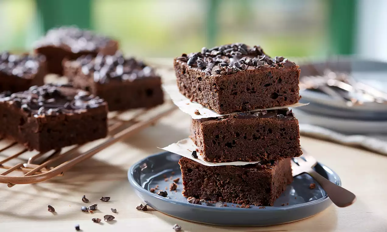 Negrese dense și lucioase, cu suprafață ușor crocantă presărată cu fulgi de ciocolată, așezate pe hârtie albă într-un platou gri