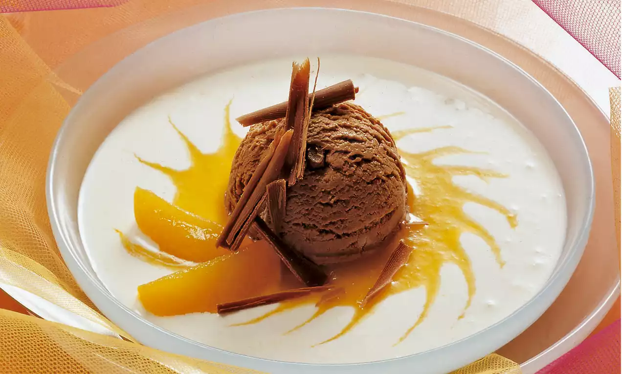 Parfait al cioccolato marrone scuro con ciuffi di scaglie di cioccolato su crema bianca decorata con spicchi di albicocca e vortici dorati