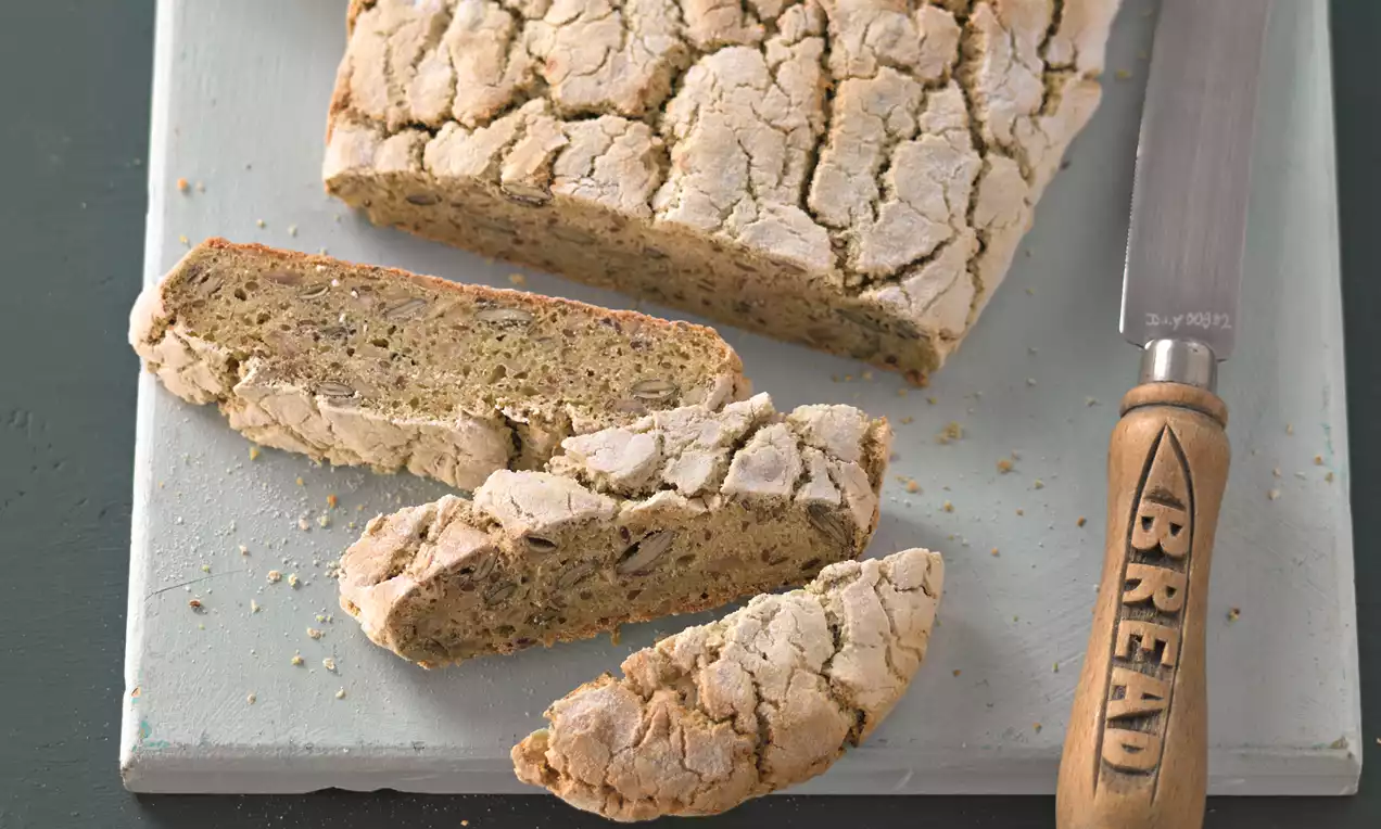 Vaalea, rustiikkinen hiivaleipä, pinnalta halkeillut ja rouheapintainen, siivutettuna puiselle alustalle leipäveitsen vieressä