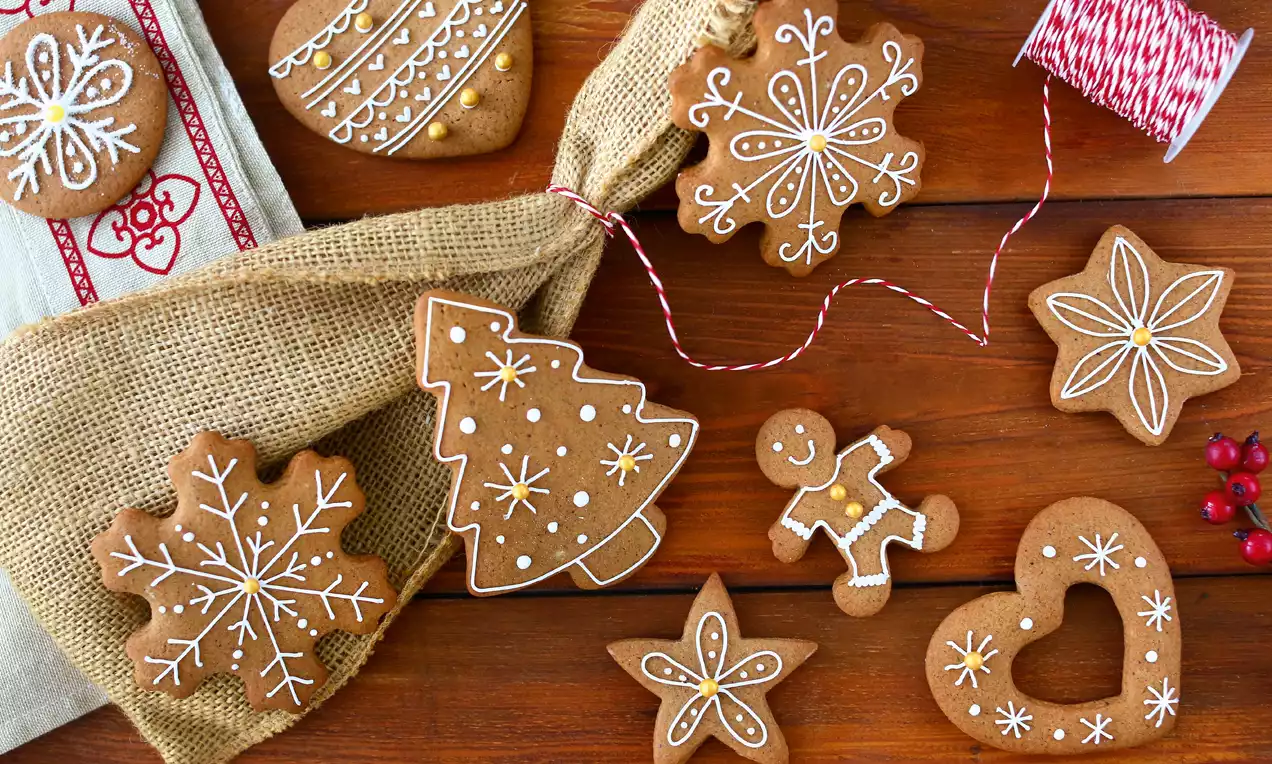 Lebkuchen biscuits with rich brown tones, intricate white icing patterns on wood, burlap accents and a spool of red-and-white twine