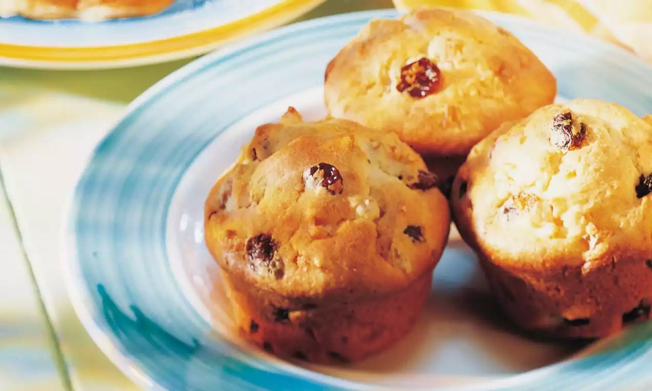 Petits pains dorés et moelleux parsemés de raisins secs, disposés sur une assiette à motifs bleu et blanc