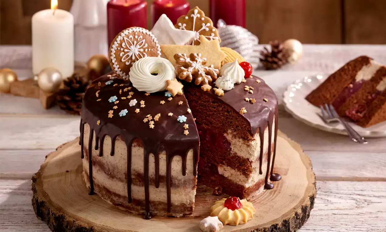 Weihnachtliche Torte mit dunklem Schokoladenguss, goldenen Sternen und Keksen, auf hellem Holzbrett dekorativ angerichtet