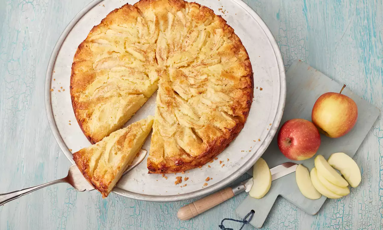 Schneller Apfelkuchen in der Springform mit goldbrauner Kruste, hellen, dünnen Apfelscheiben, Zimt‑Zucker bestreut und leichtem Puderzucker